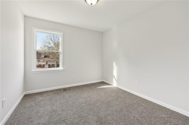 spare room featuring a textured ceiling, carpet, visible vents, and baseboards