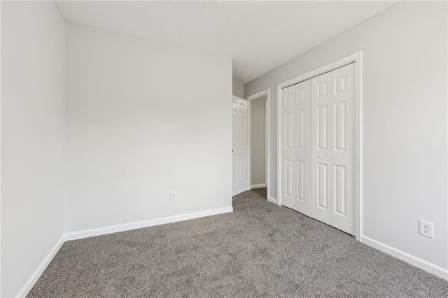 unfurnished bedroom with carpet floors, a closet, and baseboards