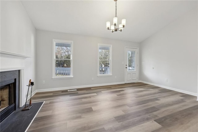 unfurnished living room featuring a premium fireplace, baseboards, and wood finished floors