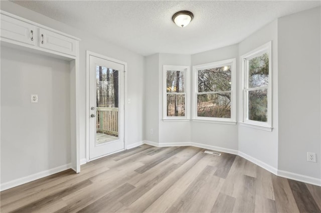 unfurnished dining area featuring baseboards, plenty of natural light, and light wood-style floors