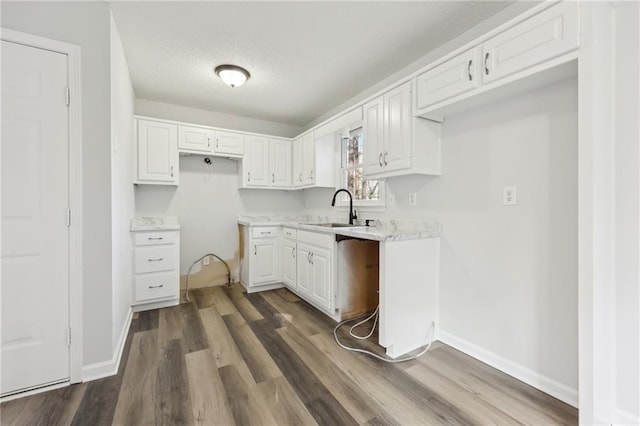 kitchen featuring dark wood finished floors, white cabinetry, light countertops, and a sink