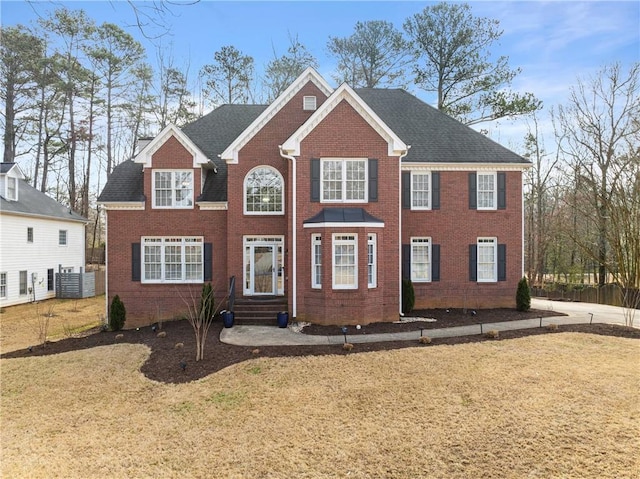 colonial-style house with brick siding and a front lawn