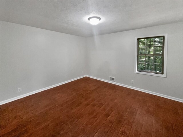 unfurnished room with a textured ceiling and hardwood / wood-style floors