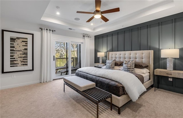 bedroom featuring light carpet, visible vents, access to exterior, a tray ceiling, and a decorative wall