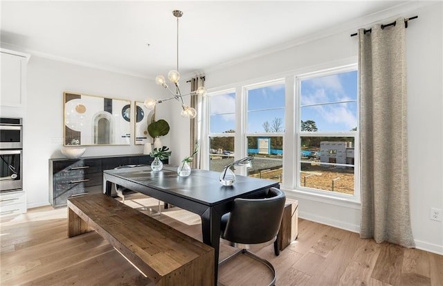 dining room featuring light wood-type flooring, an inviting chandelier, baseboards, and crown molding