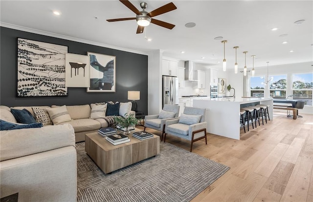 living area with light wood finished floors, ceiling fan, crown molding, and recessed lighting