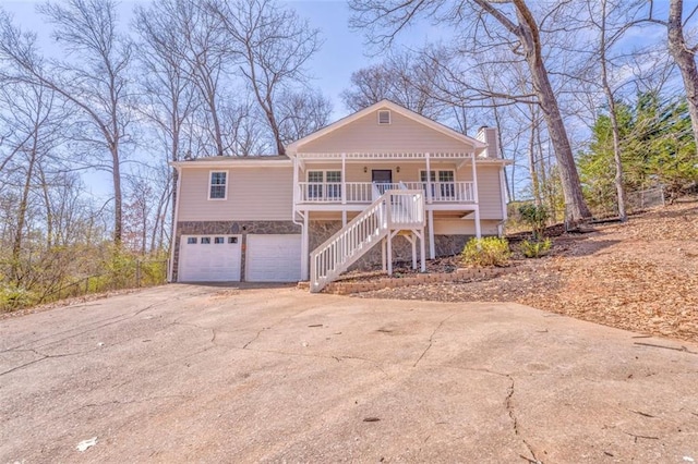 view of front of home with driveway, stone siding, a chimney, stairs, and a porch