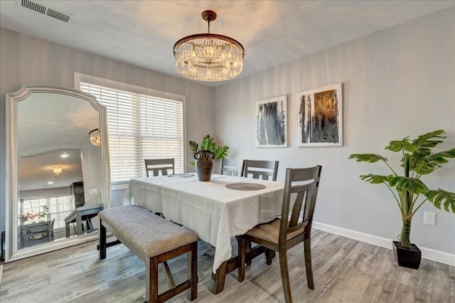 dining area featuring an inviting chandelier, light wood-style flooring, visible vents, and a wealth of natural light