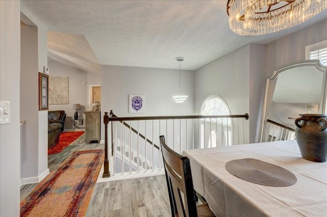 dining space with a notable chandelier, a textured ceiling, baseboards, and wood finished floors