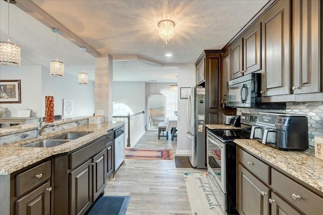 kitchen featuring a sink, decorative backsplash, dark brown cabinetry, stainless steel appliances, and light wood-style floors