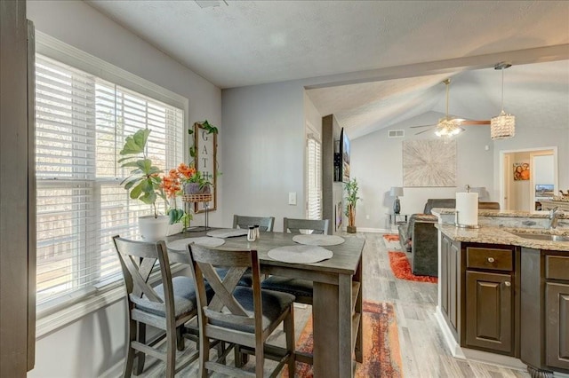 dining area featuring visible vents, baseboards, lofted ceiling, light wood-style floors, and a ceiling fan