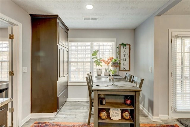 dining space featuring light wood-style floors, visible vents, and a wealth of natural light