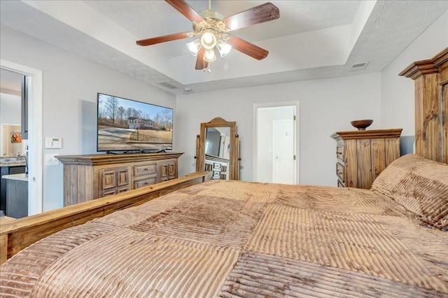 bedroom with a tray ceiling, a ceiling fan, and visible vents