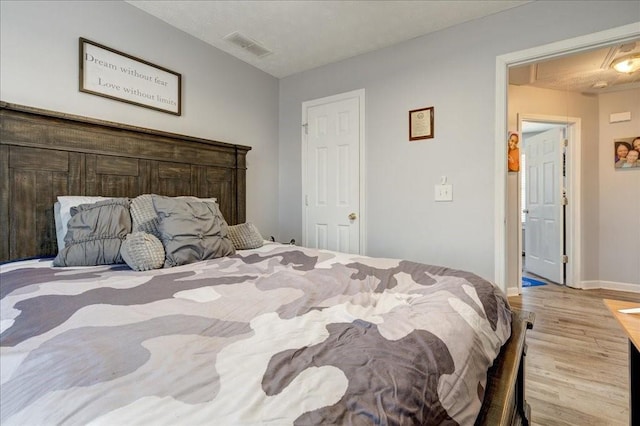 bedroom with visible vents, baseboards, and wood finished floors