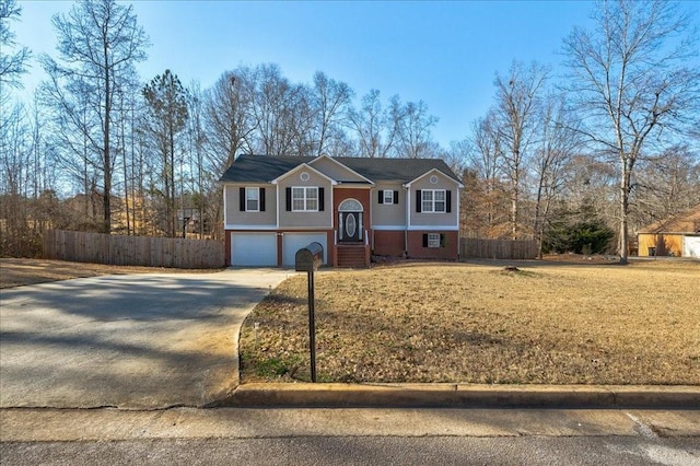 split foyer home with brick siding, driveway, a garage, and fence