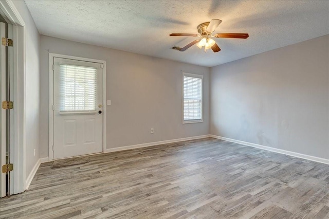 spare room featuring visible vents, a ceiling fan, a textured ceiling, wood finished floors, and baseboards