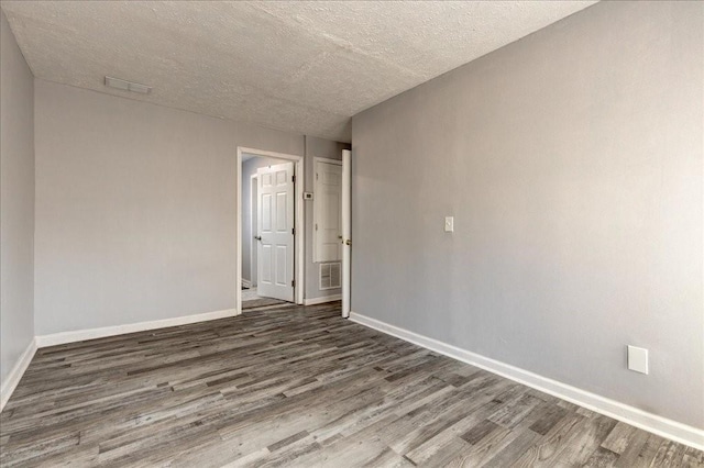 unfurnished room featuring visible vents, baseboards, and wood finished floors