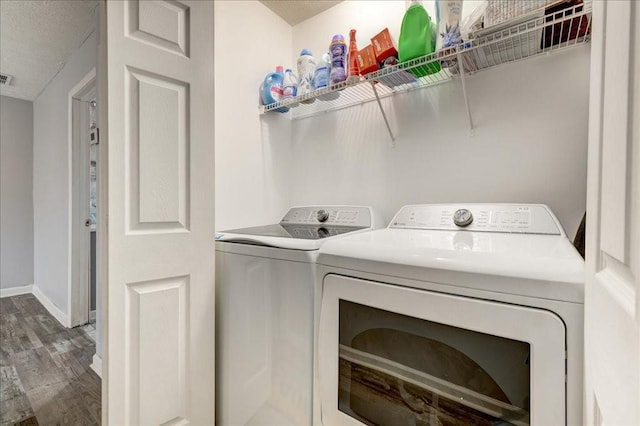 clothes washing area with visible vents, baseboards, laundry area, wood finished floors, and separate washer and dryer