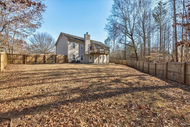 rear view of house featuring a yard, a chimney, and a fenced backyard