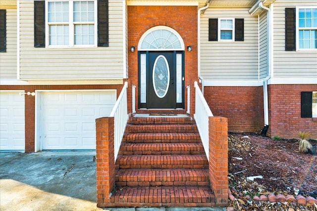 view of exterior entry with brick siding, driveway, and an attached garage