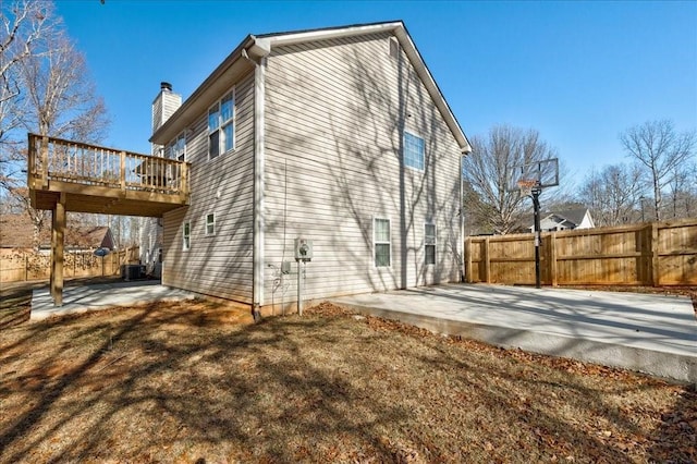 view of side of property with a chimney, a patio area, fence, and a wooden deck