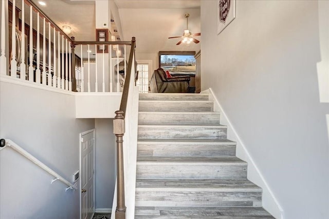 stairway with a high ceiling, baseboards, and ceiling fan