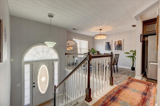 entryway with visible vents, baseboards, and an inviting chandelier