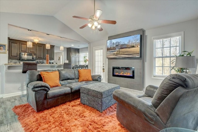 living area featuring lofted ceiling, plenty of natural light, light wood-style floors, and a large fireplace