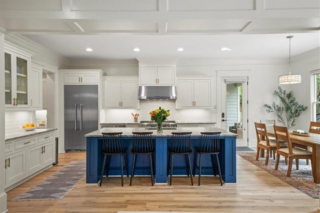 4048 Navajo Trl, Brookhaven, GA 30319 - kitchen featuring built in refrigerator, under cabinet range hood, light wood-style floors, a breakfast bar area, and decorative backsplash