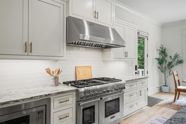 4048 Navajo Trl, Brookhaven, GA 30319 - kitchen with appliances with stainless steel finishes, under cabinet range hood, light wood-style floors, tasteful backsplash, and light stone countertops