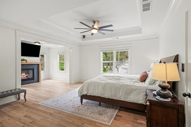 4048 Navajo Trl, Brookhaven, GA 30319 - bedroom with a tray ceiling, wood finished floors, a glass covered fireplace, crown molding, and baseboards