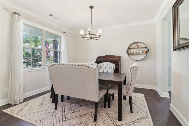 dining room featuring dark wood-style flooring, a notable chandelier, crown molding, and baseboards