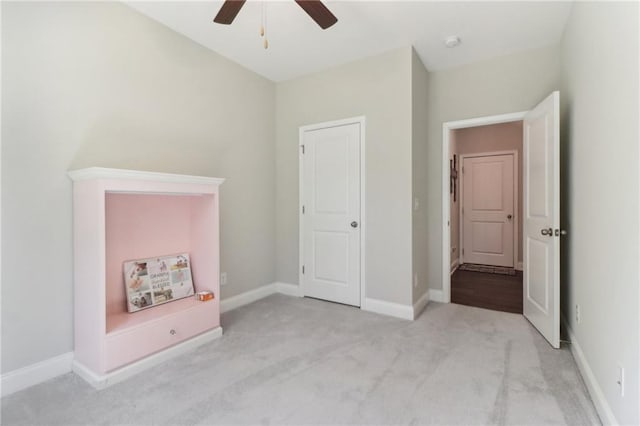 unfurnished bedroom featuring baseboards, a ceiling fan, and light colored carpet