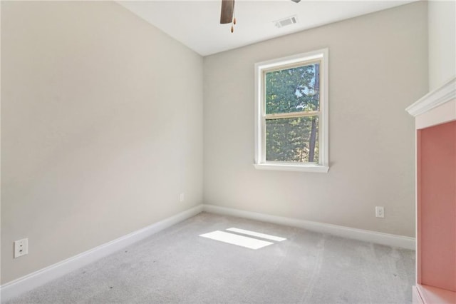 carpeted empty room with a ceiling fan, visible vents, and baseboards