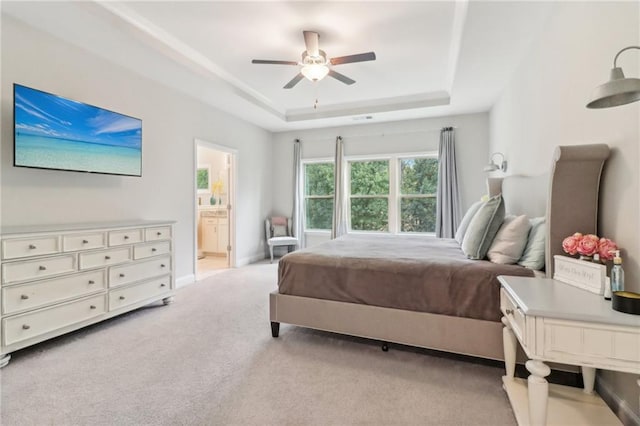 bedroom featuring a raised ceiling, a ceiling fan, light carpet, connected bathroom, and baseboards