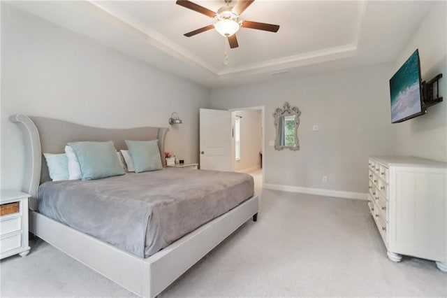 bedroom with a ceiling fan, a raised ceiling, light colored carpet, and baseboards