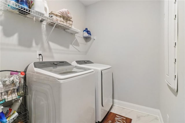 washroom featuring washing machine and dryer, laundry area, marble finish floor, and baseboards