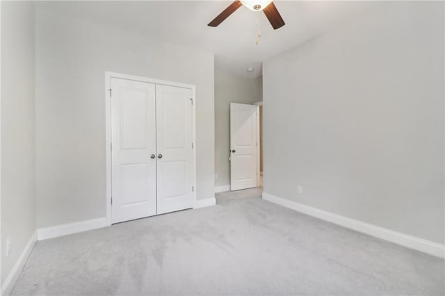 unfurnished bedroom featuring light carpet, a closet, a ceiling fan, and baseboards