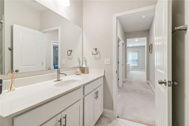 bathroom with marble finish floor, vanity, and baseboards