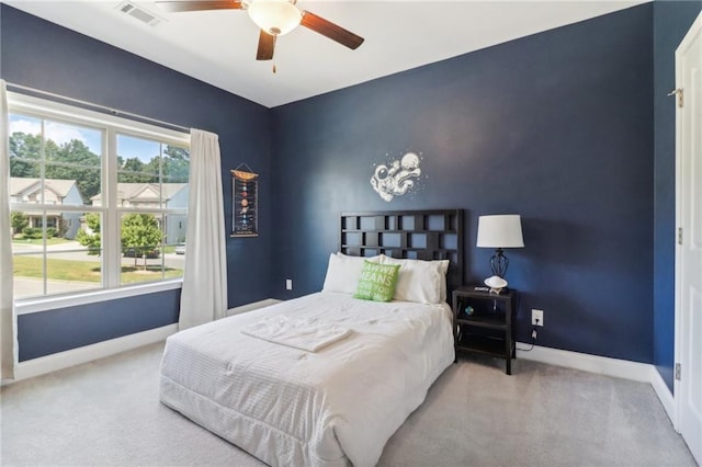 carpeted bedroom with an accent wall, a ceiling fan, visible vents, and baseboards