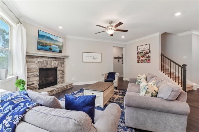 living area with baseboards, wood finished floors, stairs, crown molding, and a stone fireplace