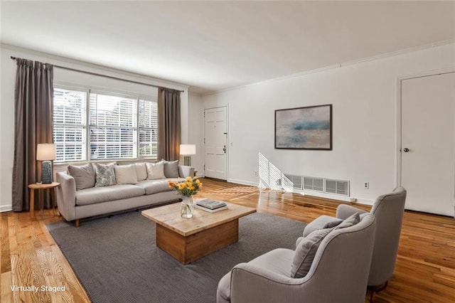 living area with baseboards, crown molding, visible vents, and wood finished floors