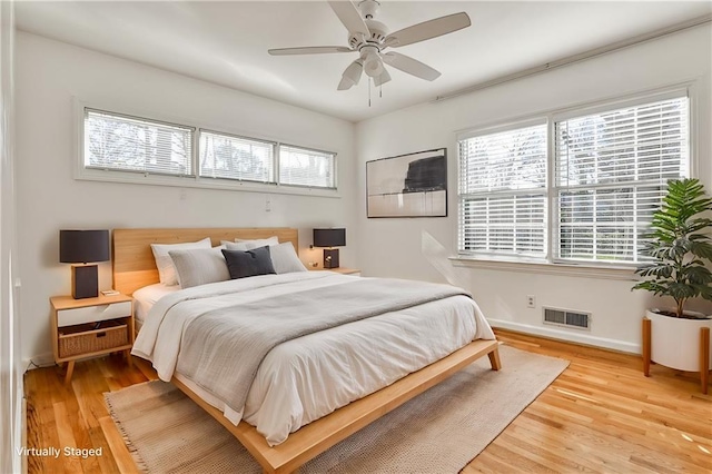 bedroom featuring a ceiling fan, baseboards, visible vents, and wood finished floors