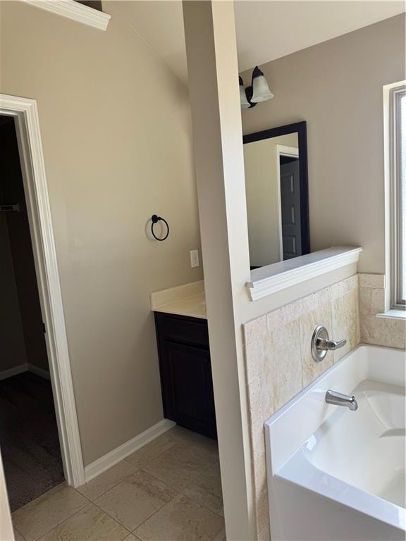 3897 Valley Bluff Ln, Snellville, GA 30039 - bathroom with a garden tub, vanity, and baseboards