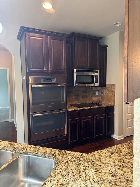 3897 Valley Bluff Ln, Snellville, GA 30039 - kitchen with appliances with stainless steel finishes, arched walkways, backsplash, light stone counters, and recessed lighting