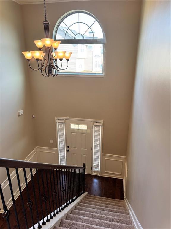 3897 Valley Bluff Ln, Snellville, GA 30039 - entrance foyer featuring a chandelier, stairs, a decorative wall, wainscoting, and wood finished floors