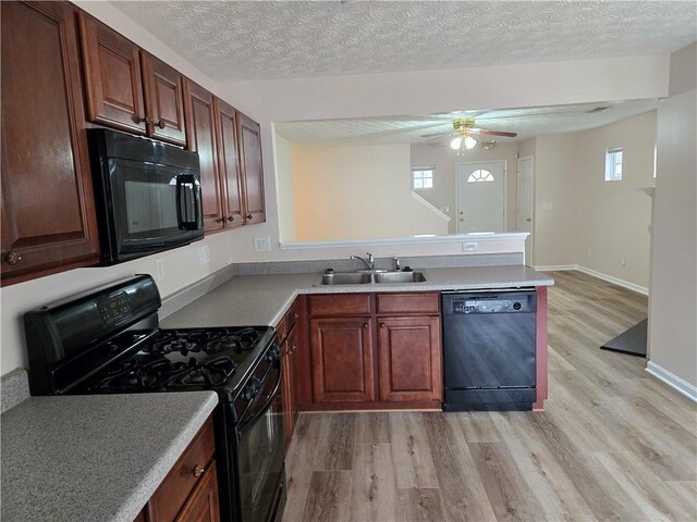 kitchen featuring decorative light fixtures, sink, light hardwood / wood-style floors, and black appliances