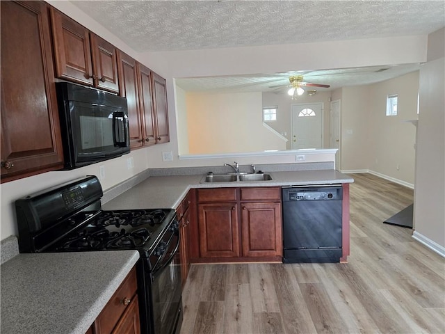 kitchen with a textured ceiling, sink, light hardwood / wood-style flooring, and black appliances