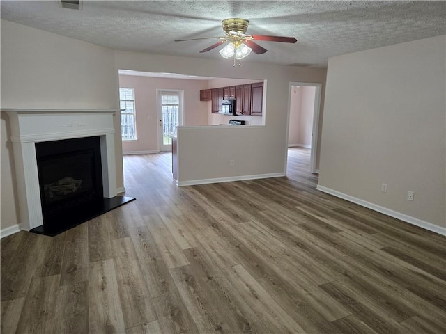 unfurnished living room featuring a textured ceiling, ceiling fan, and light hardwood / wood-style flooring