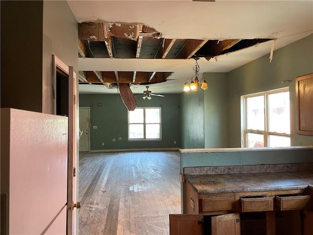 kitchen featuring wood-type flooring, ceiling fan with notable chandelier, and decorative light fixtures